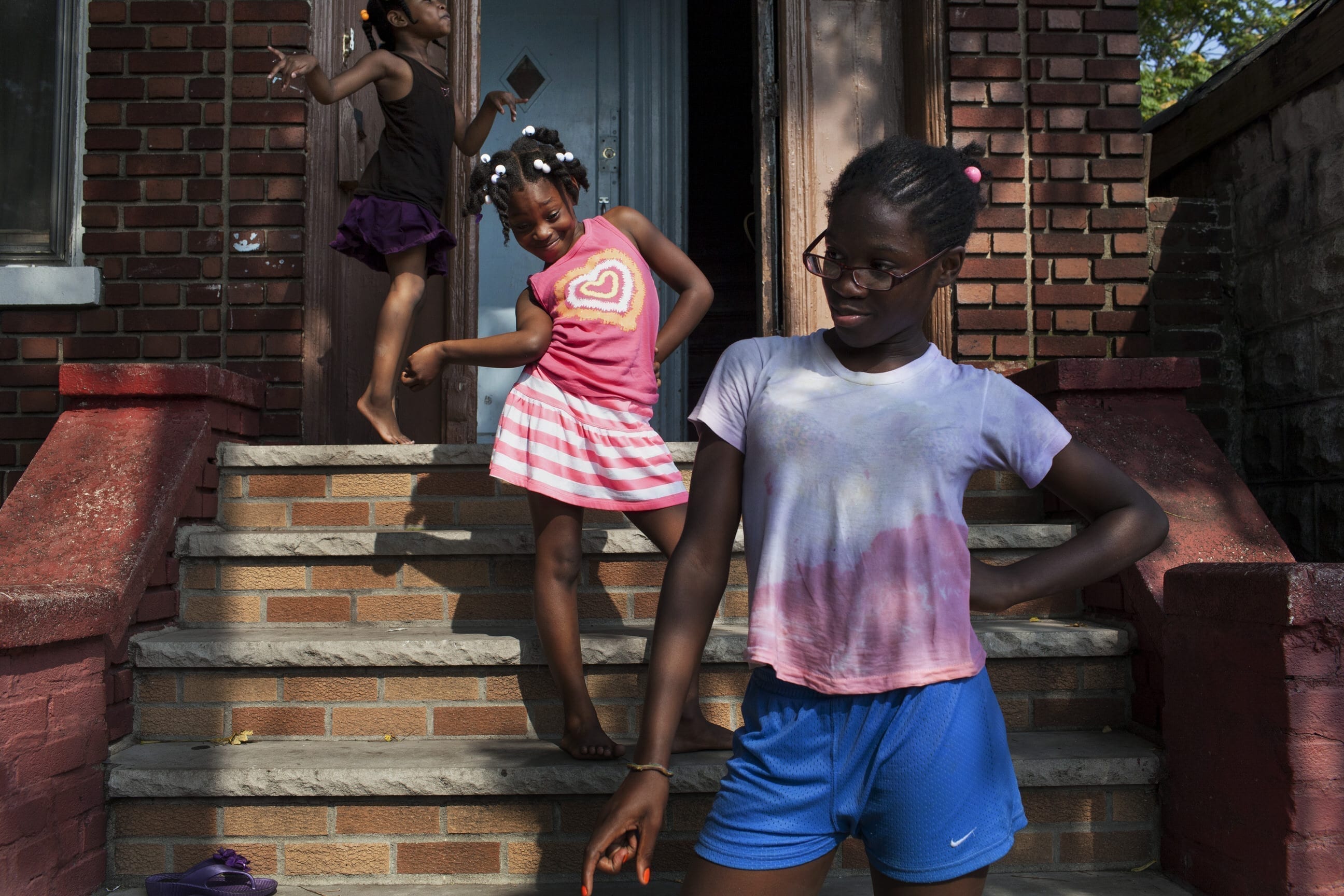 21st August, 2013. Flatbush, Brooklyn. Sarah's niece and her friends strike poses on the stoop of Sarah's home on a summer afternoon. Two months later, Sarah will be shot in the foot just a few feet from this stoop.