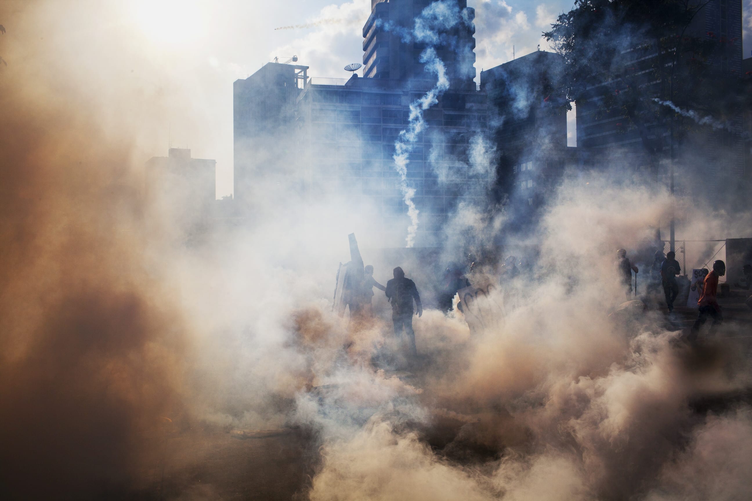 March 16, 2014. Caracas, Venezuela. Protesters stand in a cloud of tear gas as they clash with the National Guard in Altamira, a wealthy enclave of Caracas. 