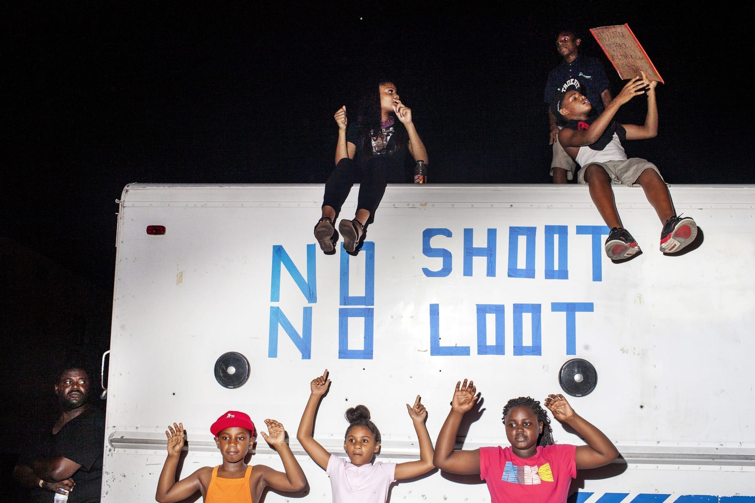 19th August, 2014. Ferguson, MO. Children dance to music playing from a truck with the words "no shoot, no loot" written on it and parked in a lot on West Florissant Ave. during a protest on 19th August 2014, in Ferguson. Moments later riot police insisted that the protesters keep marching in circles around the designated protest area and not stop to dance.
