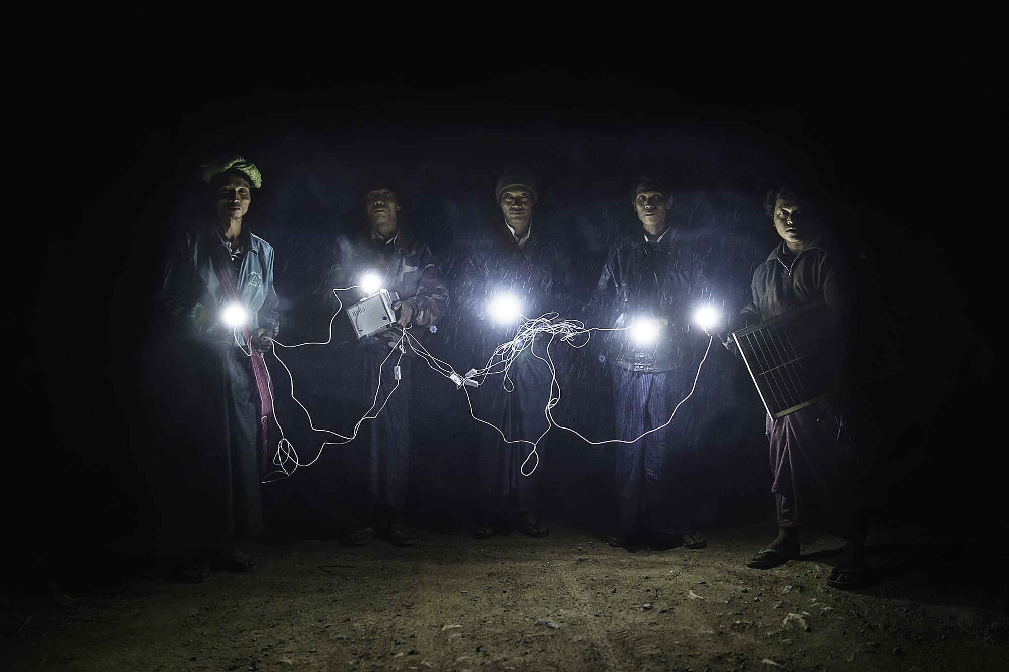 Village leaders walk through Inn Gaung Village illuminated by a solar panel energy system.