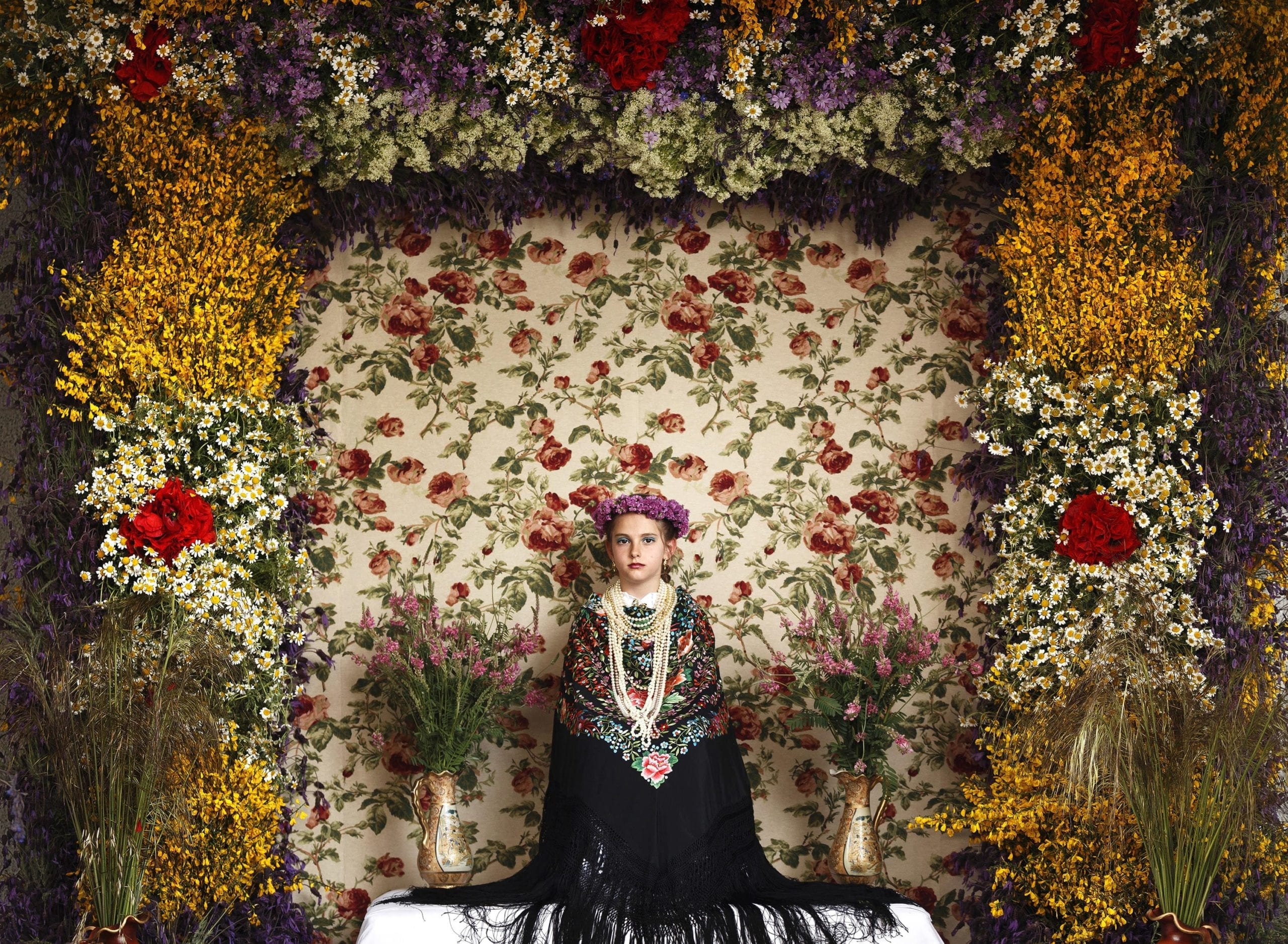 A 'Maya' girl sits in an altar during the traditional celebration of 'Las Mayas' on the streets of the small village of Colmenar Viejo, near Madrid, Spain Saturday, May 2, 2015. The festivity of 'Las Mayas' comes from pagan rites and dates from at least the medieval age, appearing in ancient documents. It takes place every year in the beginning of May and celebrates the arrival of the spring. A girl between 7 and 11years is chosen as 'Maya' and should sit still, serious, and quiet for a couple of hours in an altar on the street decorated with flowers and plants, afterwards they walk to the church with their family where they attend a ceremony. Not more than four, or five girls are chosen as a Maya each year.