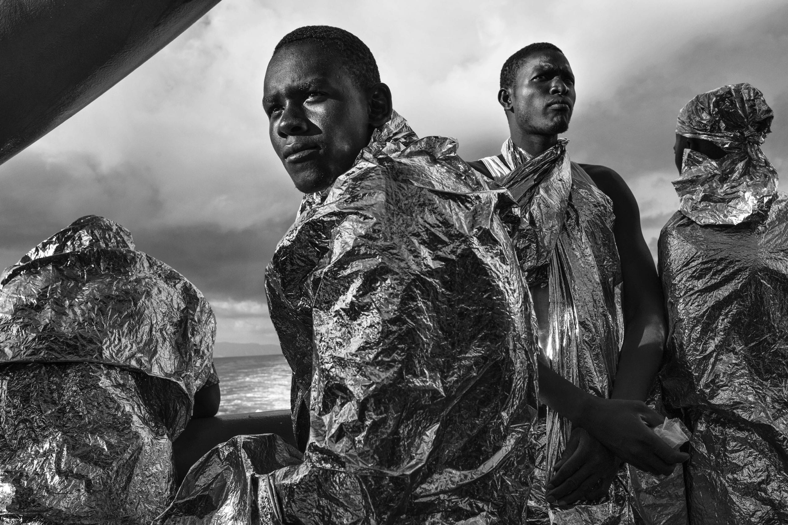 After spending two days and two nights sailing on the Mediterranean Sea on the deck of the M.S.F. (Médecins Sans Frontières - Doctors Without Borders) search and rescue ship Bourbon Argos, rescued migrants - still wrapped in their emergency blankets - catch sight of the Italian coast for the first time soon after dawn. 23 August 2015. In 2015 the ever-increasing number of migrants attempting to cross the Mediterranean Sea on unseaworthy vessels towards Europe led to an unprecedented crisis. Nearly 120 thousand people have reached Italy in the first 8 months of the year. While the European governments struggled to deal with the influx, the death toll in the Mediterranean reached record numbers. Early in May the international medical relief organization Médecins Sans Frontières (M.S.F.) joined in the search and rescue operations led in the Mediterranean Sea and launched three ships at different stages: the Phoenix (run by the Migrant Offshore Aid Station), the Bourbon Argos and Dignity (c) Francesco Zizola