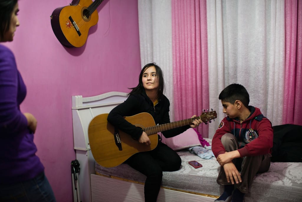 KABUL, AFGHANISTAN | 2015-01-06 | Zhala (16) plays a cover of Avril Lavigne's song in her room while her younger brother and older sister sing along.