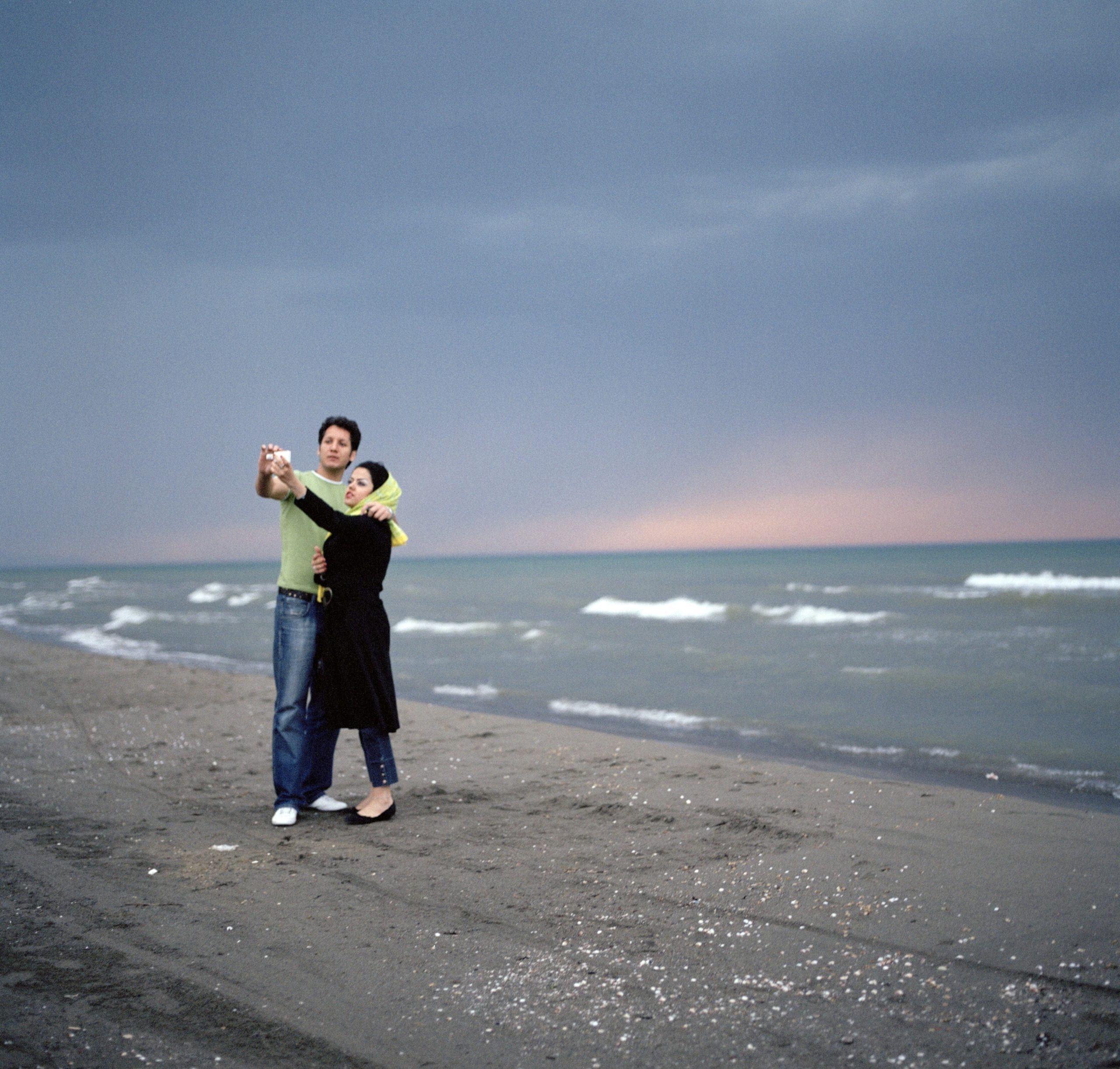 A couple photograph themselves on their mobile phone in front of the Caspian Sea © Olivia Arthur/Magnum Photos