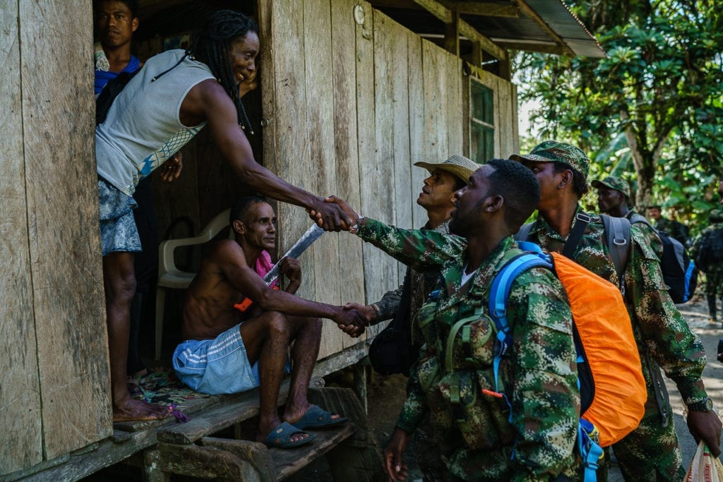 FARC guerrillas greet local farmers as they pass by. In numerous places in Colombia, the civil population know of no law and order other than from the rebel group. 1 May 2016 Photo © Federico Rios