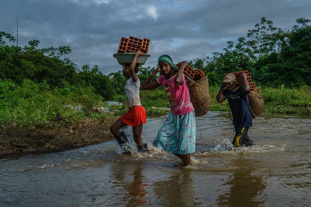 Community residents help unload the boat which was just rescued by the FARC. The bricks are meant to be used for a school nearby. The state provides the bricks but the community has to build the school. 1 May 2016. Photo © Federico Rios