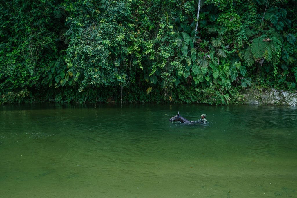 A FARC rebel rides a horse through a river and towards a clandestine route hidden in the mountains. 2 May 2016. Photo © Federico Rios