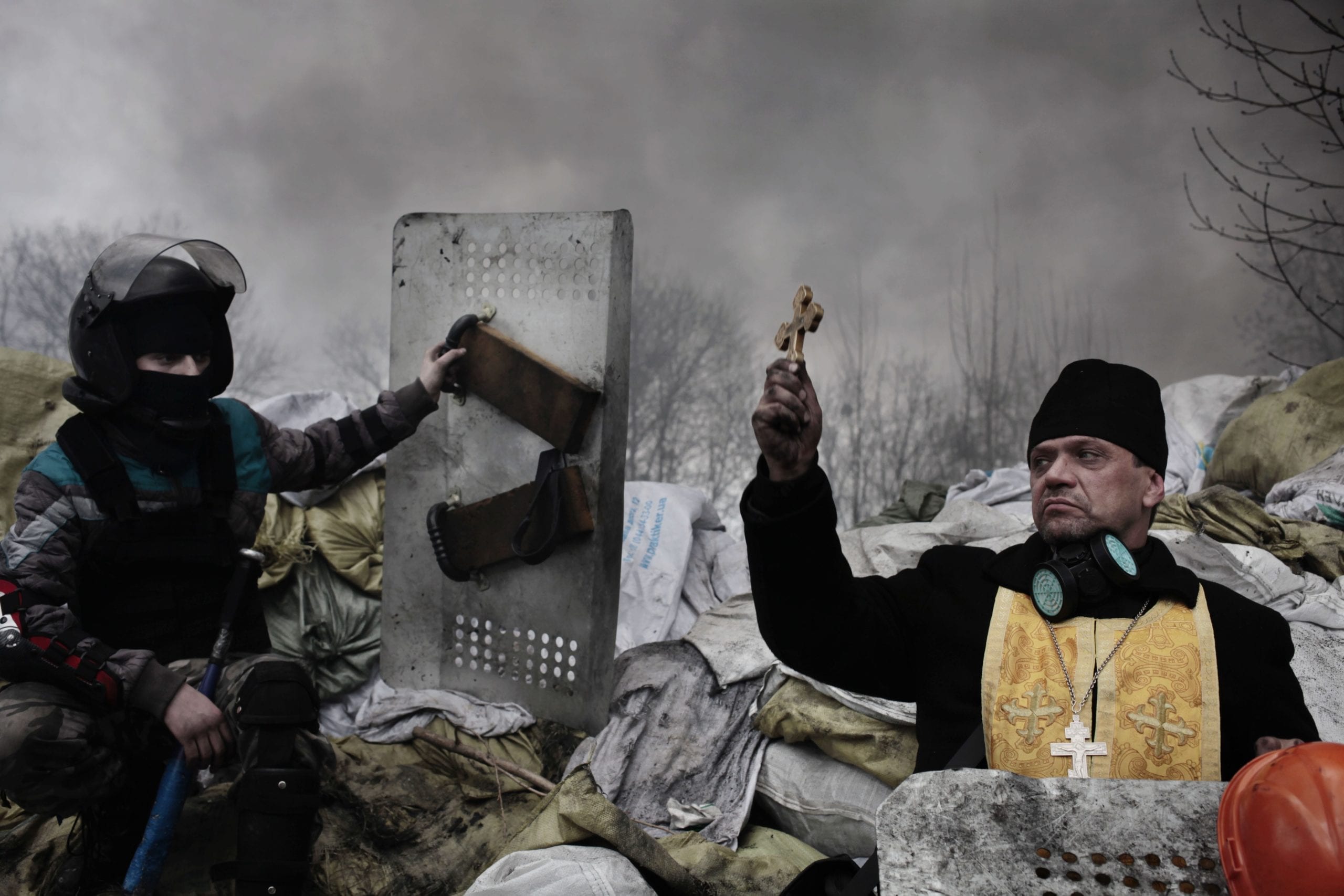 UKRAINE. Kiev. An Orthodox priest blesses the protesters on a barricade. February 20, 2014. Unidentified snipers opened fire on unarmed protesters as they were advancing on Instituska street. According to an official source, 70 protesters were shot dead. Ukrainian riot police claimed that several policeman were wounded or shot dead by snipers as well. An unofficial source said that snipers opened fire on the police and protesters at the same time in order to provoke both camps. Image (c) Jerome Sessini, courtesy Magnum Photos
