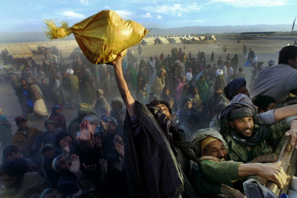 Afghan refugees at Kili Faizo refugee camp desparately reach for bags of rice and sugar being handed out by a local NGO on Dec.4th,01. The camp is near to the Chaman,Pakistan border with Afghanistan. According to UNHCR an estimated 160,000 Afghans have crossed the border to Pakistan since September 11th. Photo Paula Bronstein/ Getty Images