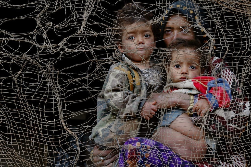 A mother and two children look out from cave dwelling