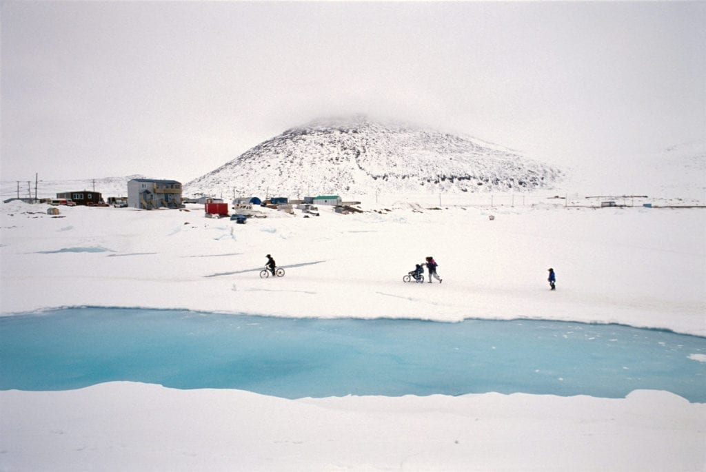 CANADA. Nunavut. Qikiqtarjuaq. 2004. A family walking with their baby stroller on the ice of the Qikiqtarjuaq bay. Qikiqtarjuaq, like many Inuit villages, was a result of forced settlement of nomadic communities. Many of their problems are born from the very difficult transition from nomadism to a permanent, as found 'in the south'.