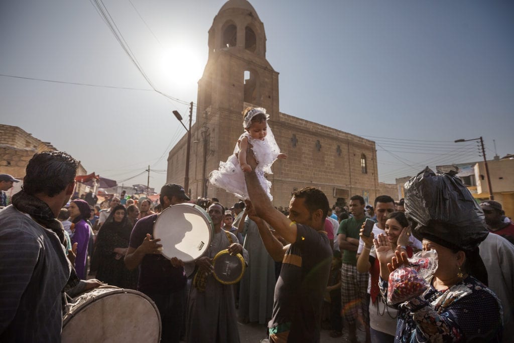 A family celerates a baptism as part of the moulid festival in Minya. Families from across Egypt make their way to Minya during the week of the festival in hopes of having their babies baptized as they believe it will bring them greater luck. After the baptismal ceremony, families parade the infants around town while bands play music to celebrate.