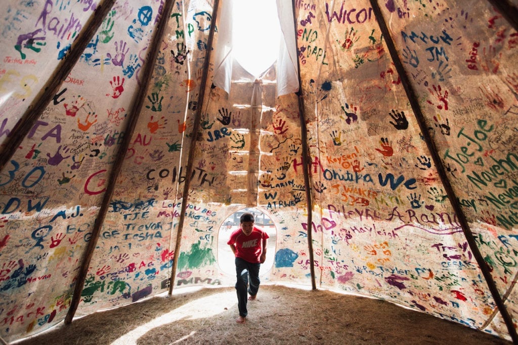 Oceti Sakowin - Oceti Sakowin, or the Seven Council Fires, is the true name of the great Sioux nation and refers to the coming together of the different factions of the tribe. Oglala, Cheyenne, Ut, Cree, Hopi and non-indigenous all are among the 200+ tribes represented in the camps and on the front lines. The last time there was a similar gathering was before the Battle of the Little Bighorn, 1876. Jesse Jaso, 12, enters the Unity Teepee, at the Sacred Stone Camp near Cannonball, ND on Saturday, September 10, 2016. The teepee is signed by camp supporters from all over North America and around the world. Amber Bracken for Buzzfeed News