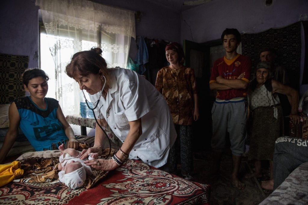 Dr. Ciupitu doing a house call to consult on an infant. The child had otitis due to improper bathing. According to Eurostat data, with an infant mortality rate of 8.4 deaths per 1000 live births in 2014, Romania ranks first among European countries (the EU rate is 3.7). Gangiova, Romania, 18 August 2016. From the series A country doctor and her calling © Ioana Moldovan, Romania, shortlist, Professional, Daily Life, 2017 Sony World Photography Awards 