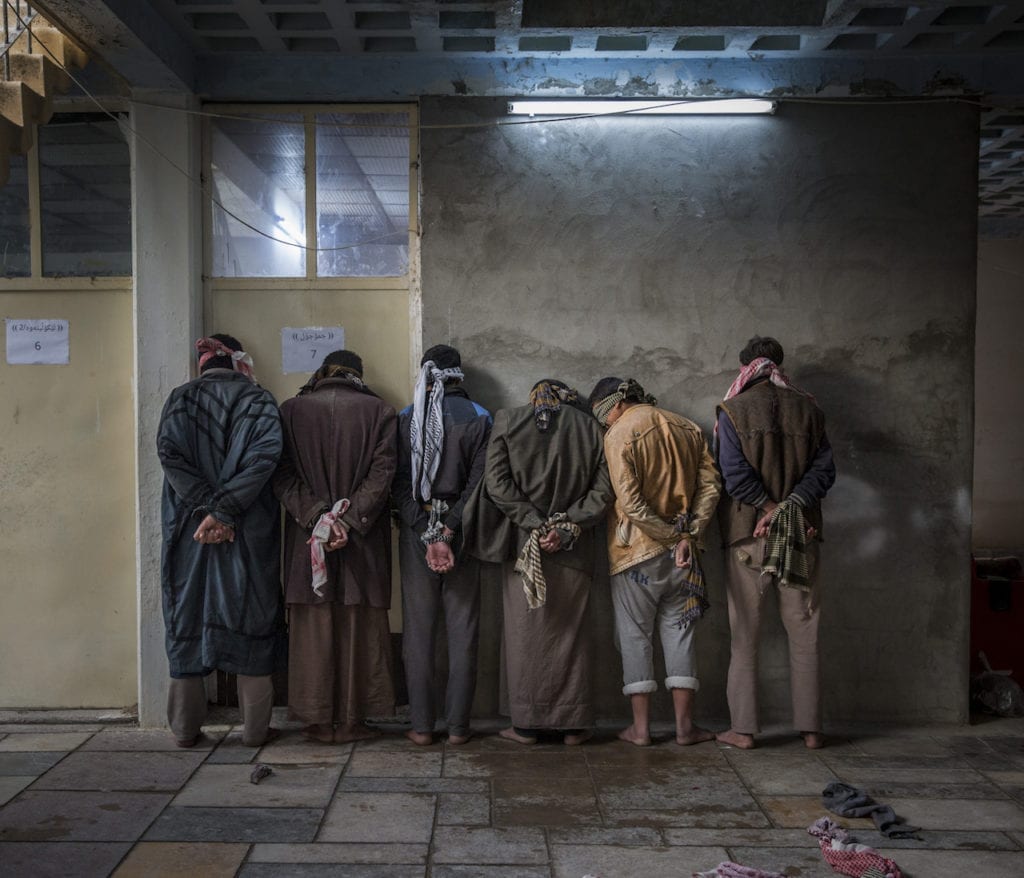 Iraqi men from the Hawija region of Iraq wait to be questioned by Kurdish security personnel at a base near Kirkuk. Having fled areas still under the control of ISIS militants, men and boys of fighting age are vetted for any links to the group before being allowed to join their families in camps for displaced people in the Kurdish controlled region of the country. From the series Caught in the Crossfire © Ivor Prickett, Ireland, shortlist, Professional Current Affairs & News, 2017 Sony World Photography Awards