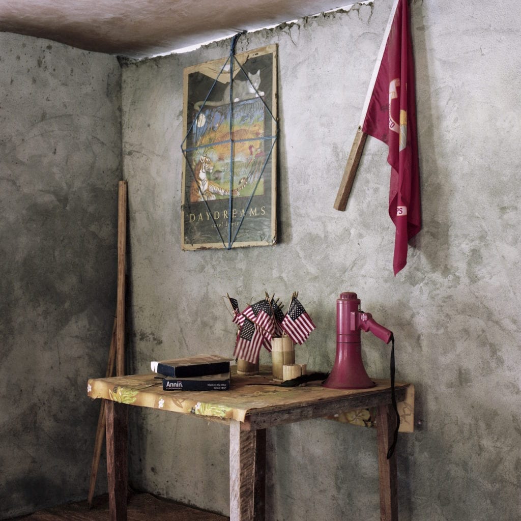 American Flags and a megaphone sits inside the headquarters of the John Frum Movement on Tanna, Vanuatu. From the series Cargo © Jon Tonks