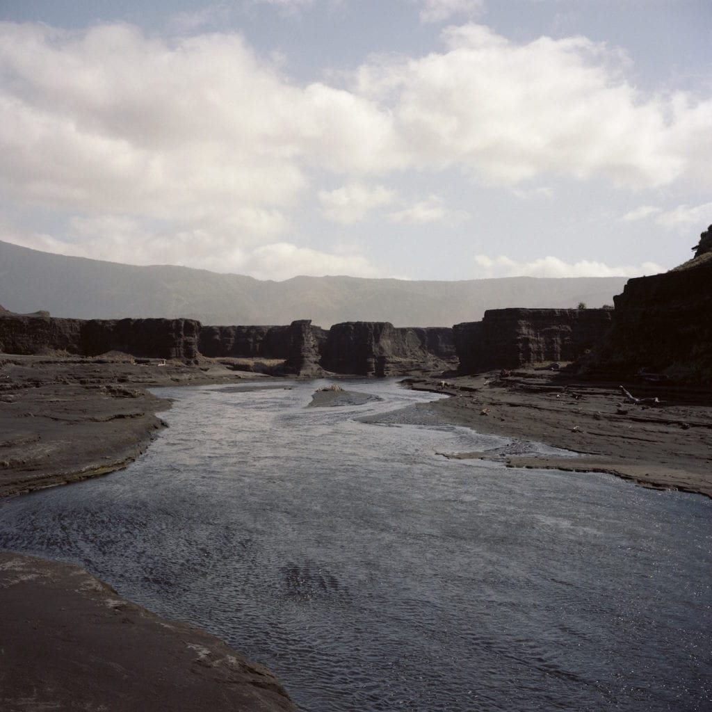 A river at Sulphur Bay cuts through the dark sand deposited from Mount Yasur, the active Volcano on Tanna, Vanuatu. From the series Cargo © Jon Tonks