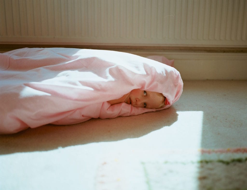 Plum cocooned by a pink duvet. From the series My Favourite Colour Was Yellow © Kirsty MacKay