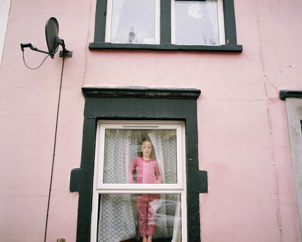 Liilly looking out from her pink house, Totterdown, Bristol. From the series My Favourite Colour Was Yellow © Kirsty MacKay