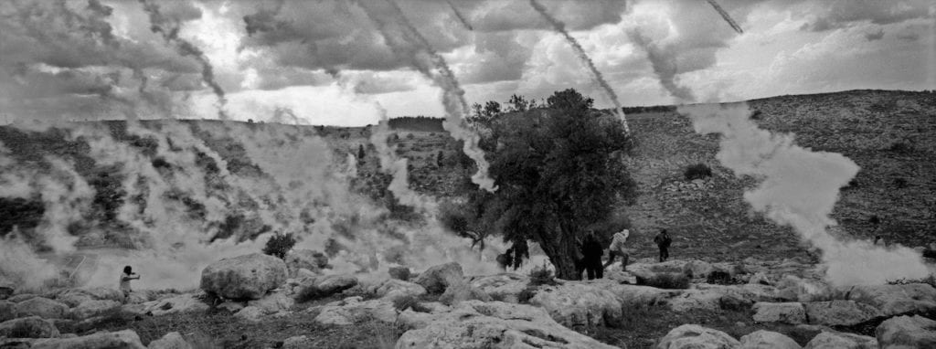 Protestor running from tear gas during riots in the Palestinian village of Nilin in the West Bank, 2010. Image © Pavel Wolberg, courtesy Prix Pictet