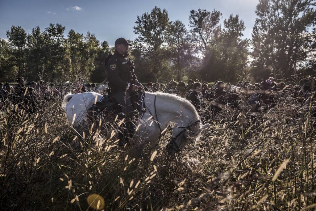 Police on horses escort hundreds of migrants after they crossed from Croatia in Dobova, Slovenia, October, 20, 2015. From the series Europe Migration Crisis © Sergey Ponomarev, courtesy Prix Pictet