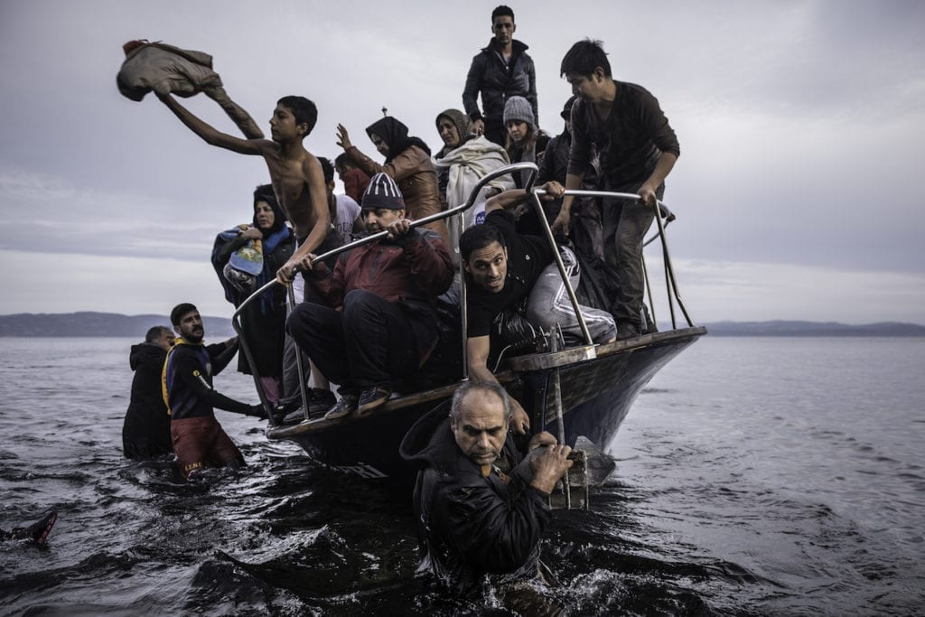 Migrants arrive by a Turkish boat near the village of Skala, on the Greek island of Lesbos. The Turkish boat owner delivered some 150 people to the Greek coast and tried to escape back to Turkey; he was arrested in Turkish waters. November 16, 2015, from the series Europe Migration Crisis © Sergey Ponomarev, courtesy Prix Pictet